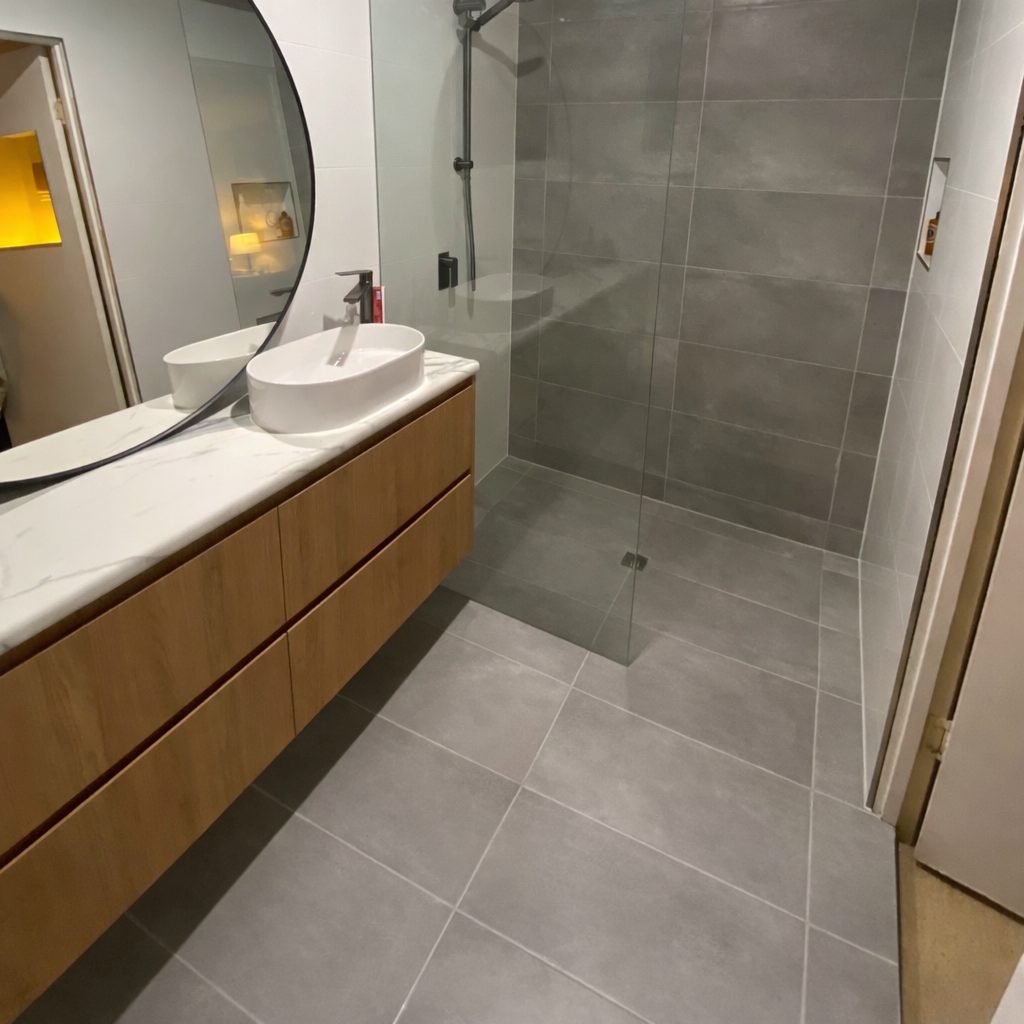 Floating timber vanity with a stone top and round black mirror