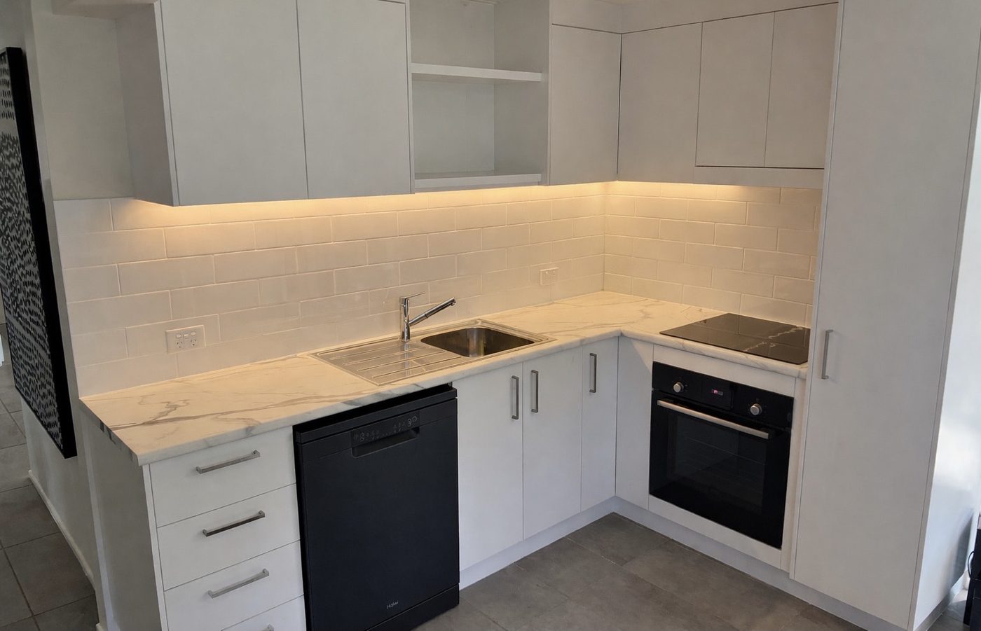 Compact white kitchen with marble-look benchtop and under-cabinet lighting